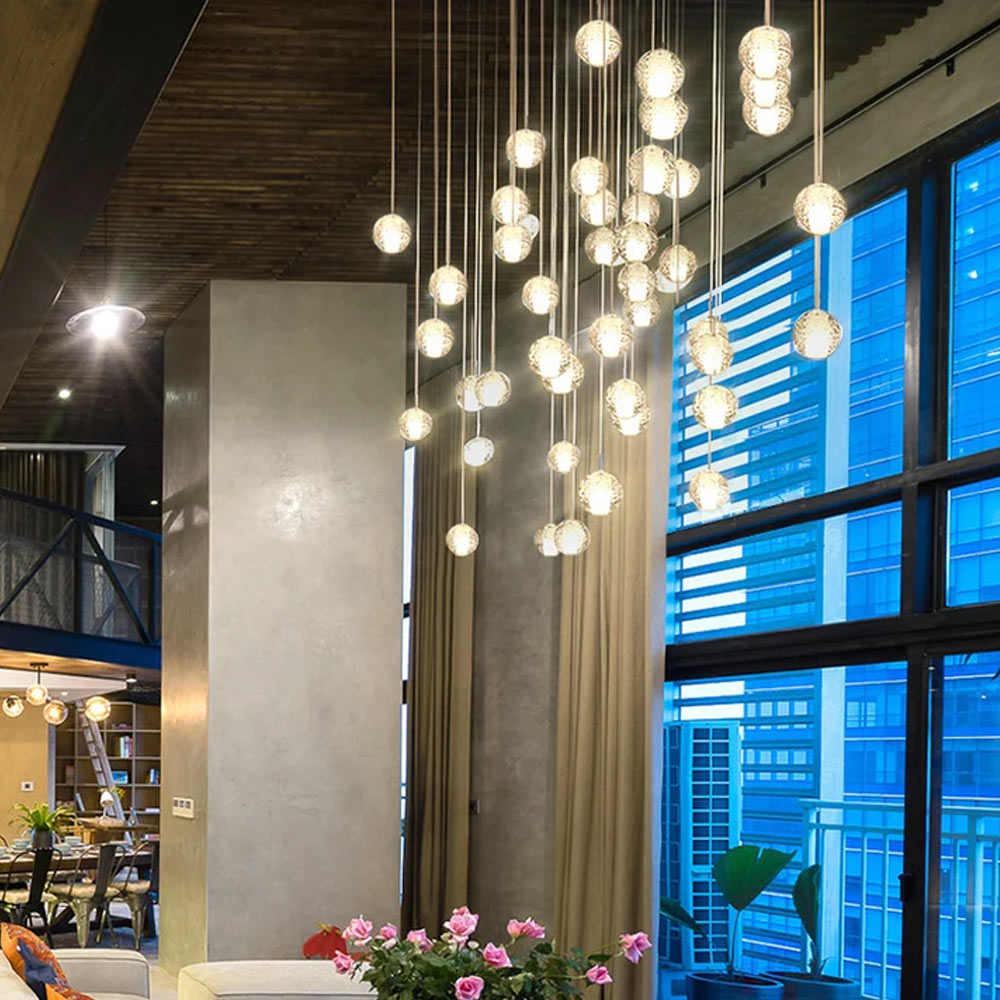 Grand 36-light crystal bubble ball chandelier cascading through high ceiling loft living room with panoramic glass windows