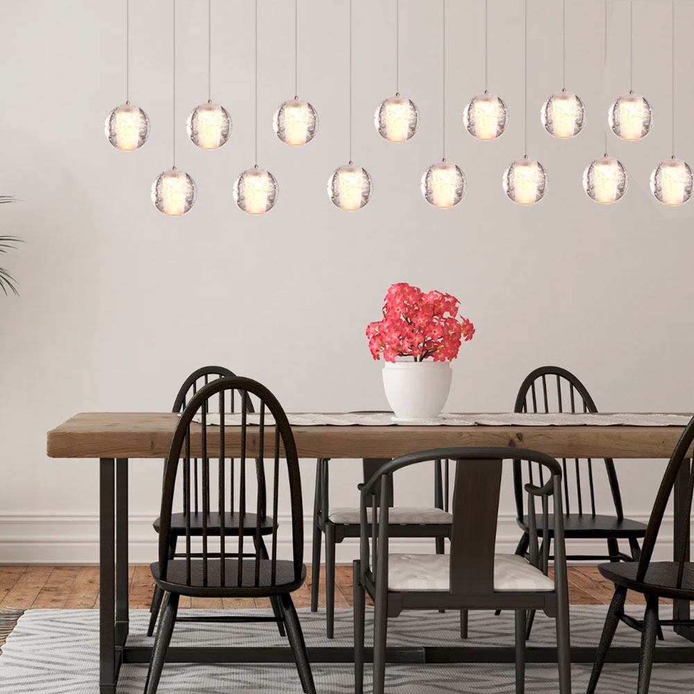 14-light linear rectangular crystal ball chandelier hanging above a rustic dining table with black chairs