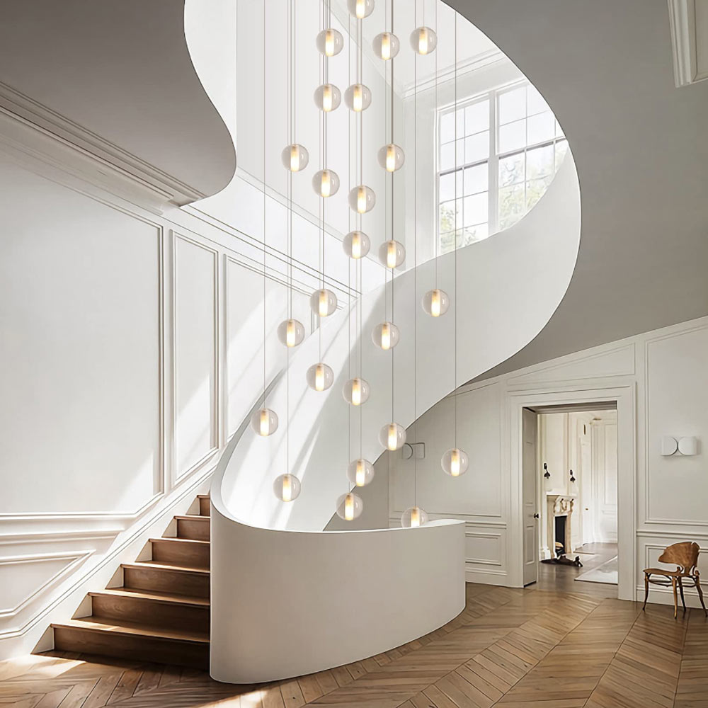 Dramatic multi-light cascading spiral crystal chandelier illuminating a luxury white curved staircase foyer with herringbone flooring