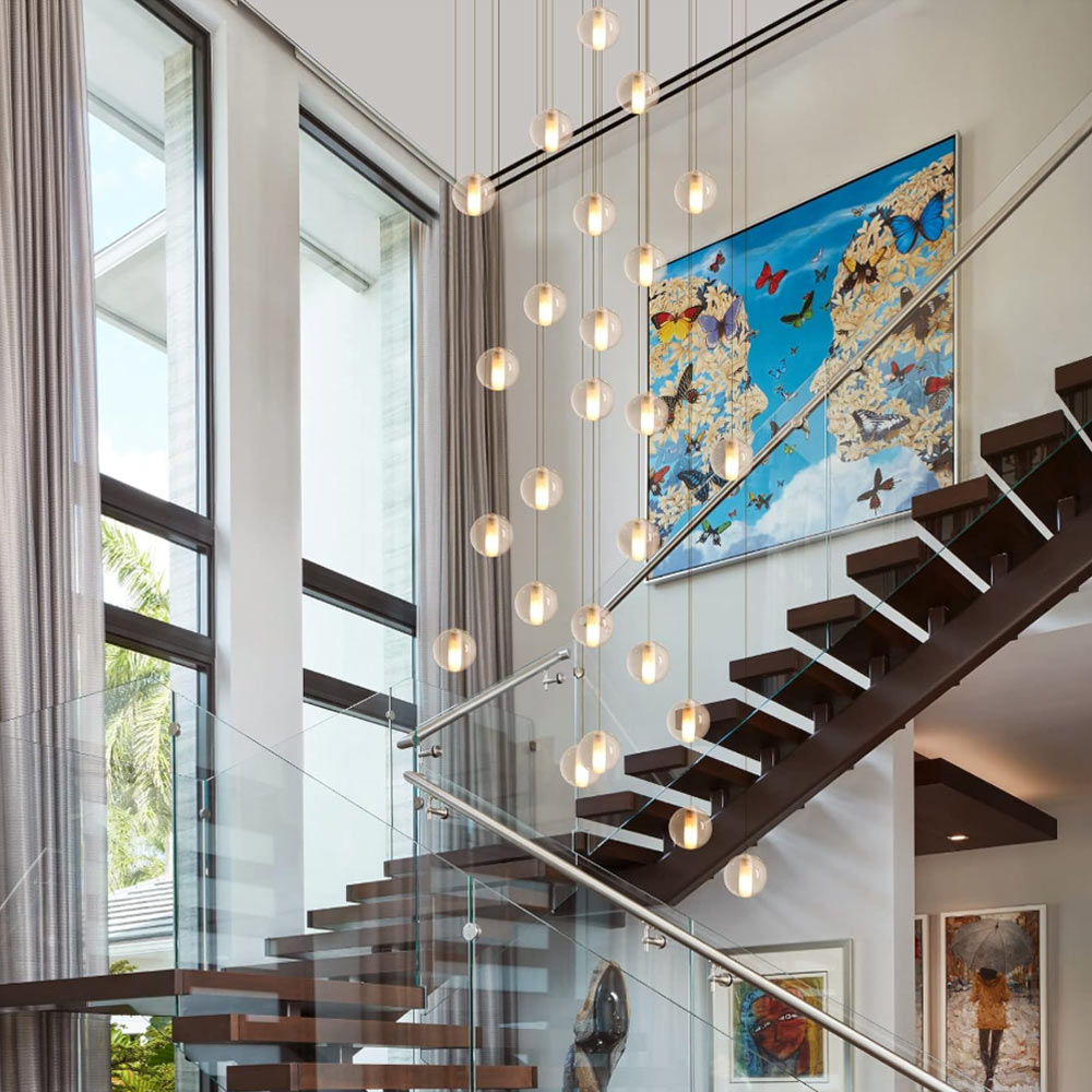 Staircase crystal bubble chandelier cascading beside modern wall art and glass railing in open-concept home