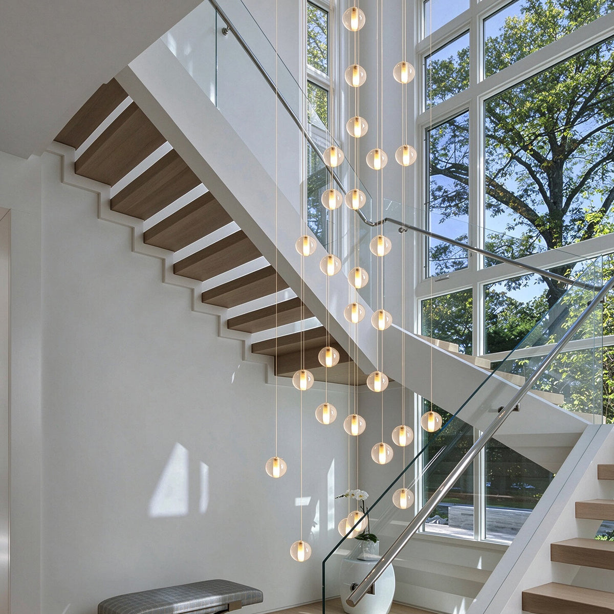 Grand 36-light cascading crystal bubble chandelier in a luxury two-story high ceiling staircase foyer with floor-to-ceiling windows