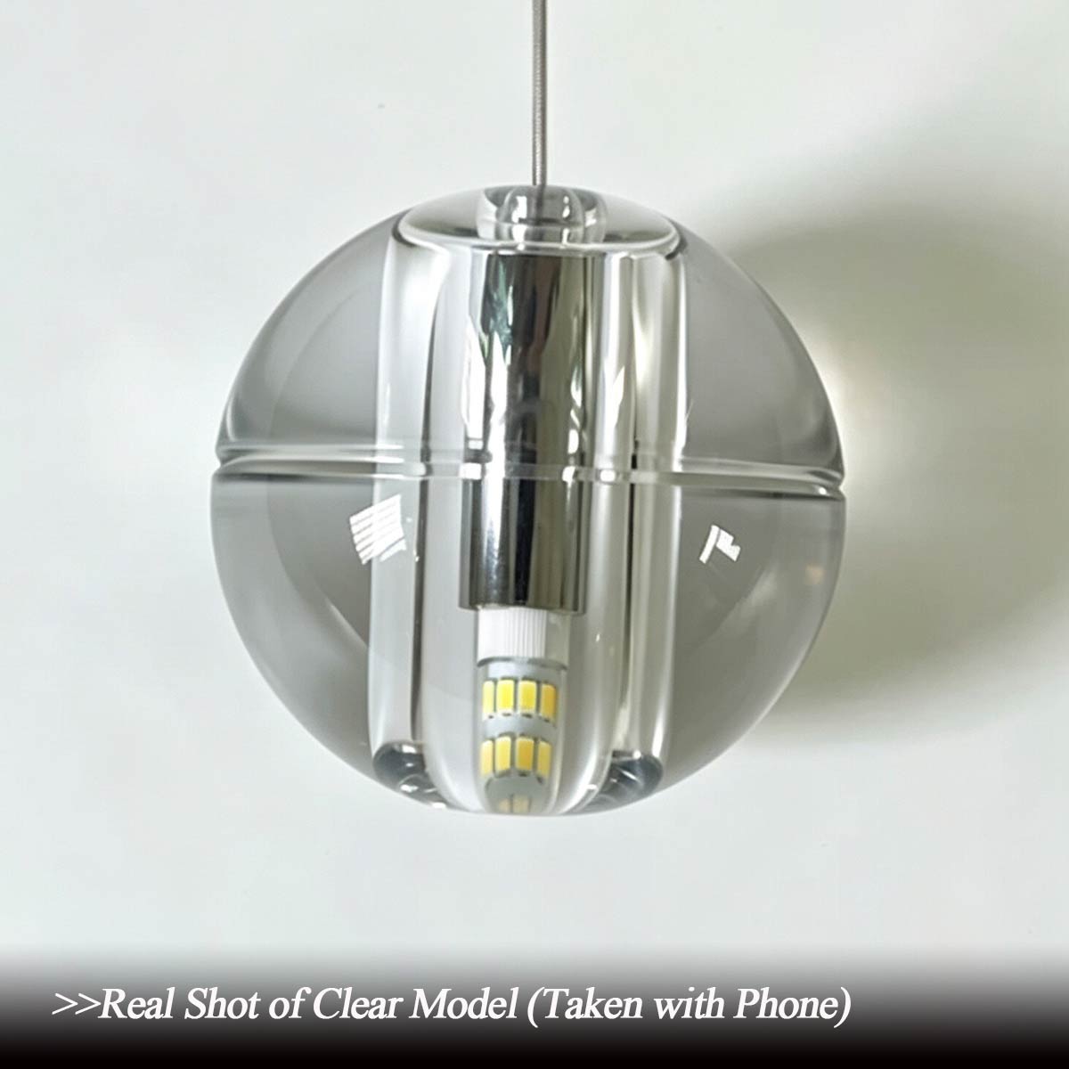 Close-up unedited phone camera shot of clear crystal model glass sphere showing solid transparent glass and internal LED bulb