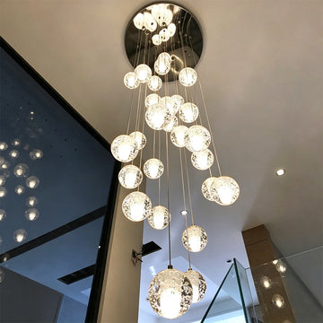 Modern spiral crystal bubble chandelier suspended from round chrome canopy in a contemporary high ceiling staircase