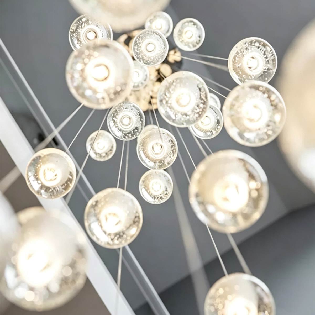 Upward view of glowing crystal bubble globes suspended on fine adjustable steel cables
