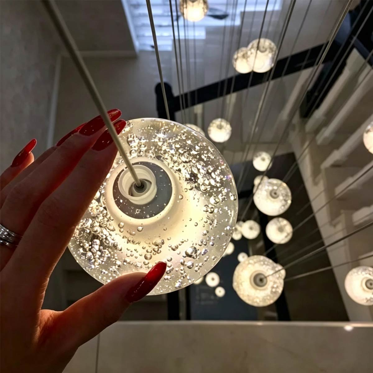 Close-up of hand holding hand-blown bubble crystal glass globe showing intricate internal air bubbles and warm LED glow