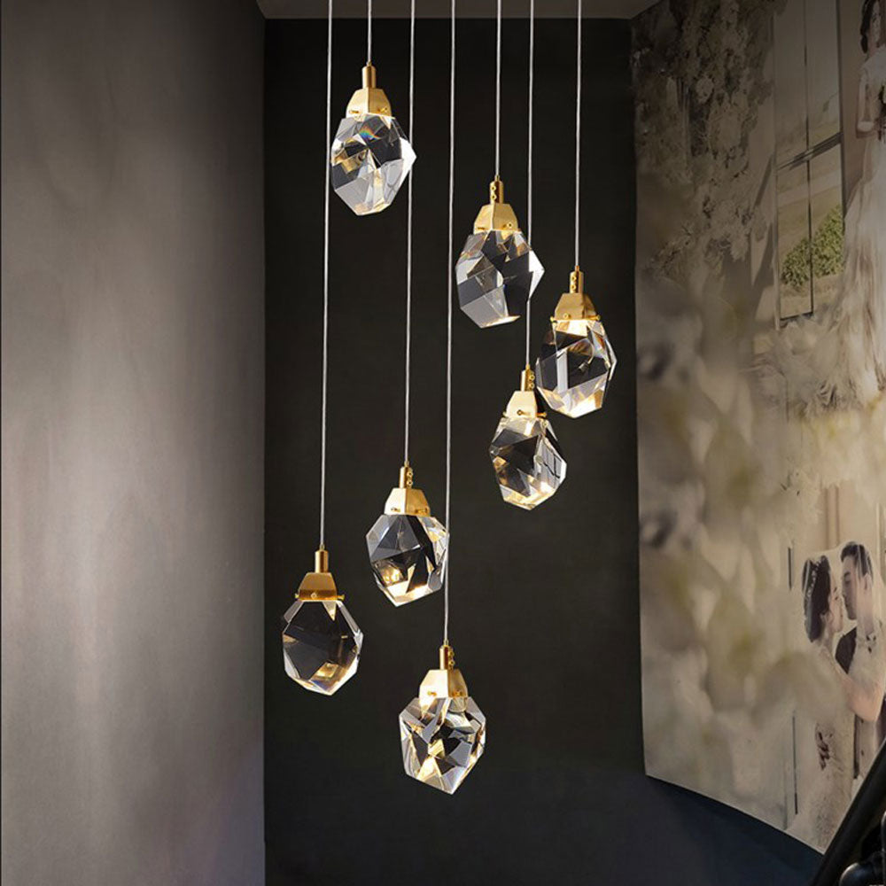 Diamond-shaped staircase chandelier with gold hardware in a grand double-height foyer