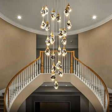 Diamond-shaped staircase chandelier with gold hardware in a grand double-height foyer