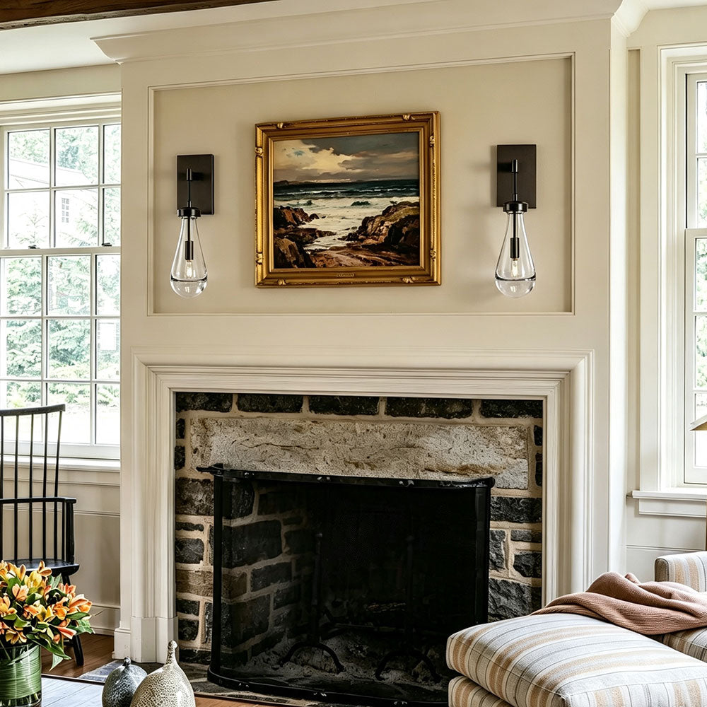 Pair brushed brass teardrop clear glass wall sconces flanking vintage painting above stone fireplace, modern farmhouse wall lamps for living room decorative wall installation