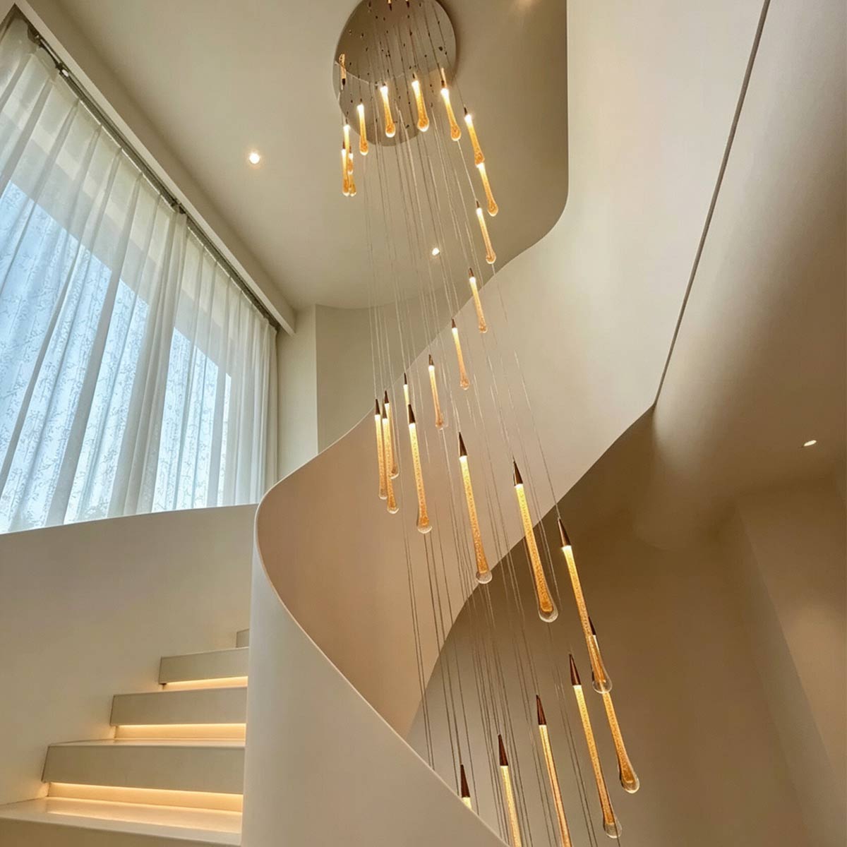 Cascading teardrop bubble crystal chandelier suspended in modern spiral staircase with warm LED lighting