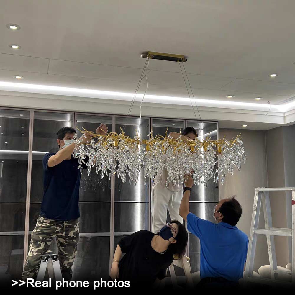 Installation process of Luxury Gold Branch Crystal Chandelier, three workers assembling the gold branch crystal pendant light on ceiling in modern interior, real phone photo
