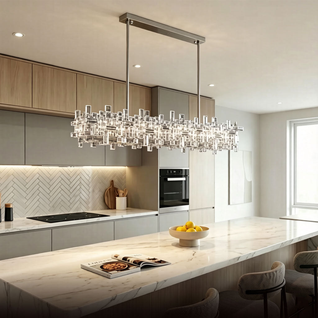 Luxury Linear Crystal Chandelier above white kitchen island in bright modern open-concept kitchen, chrome rectangular pendant light with clear crystal prisms, warm white illumination
