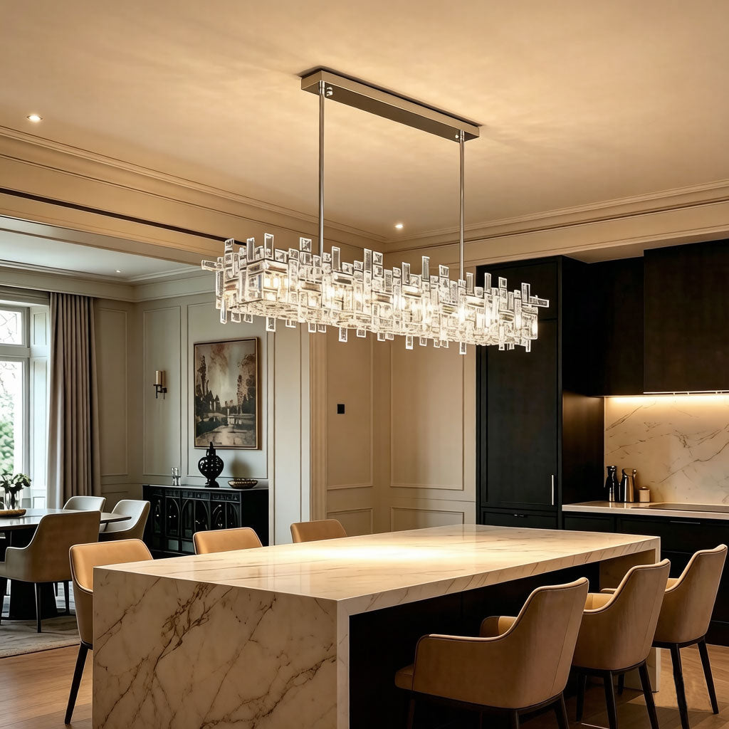 Luxury Linear Crystal Chandelier installed above marble kitchen island in elegant dining room, warm ambient glow, chrome rectangular frame with layered clear crystal prisms