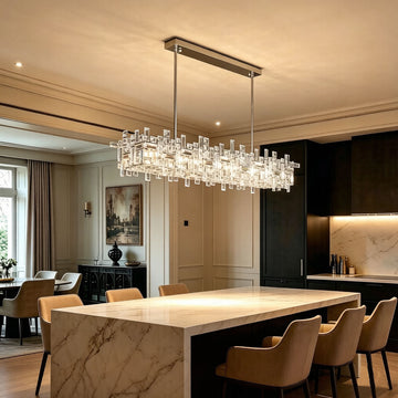Luxury Linear Crystal Chandelier installed above marble kitchen island in elegant dining room, warm ambient glow, chrome rectangular frame with layered clear crystal prisms