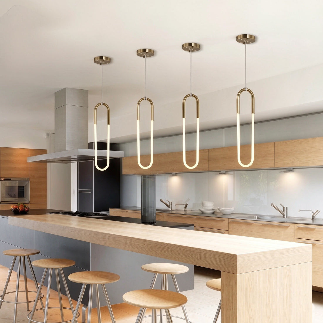 Four minimalist U-shaped gold pendant lights above modern kitchen island, brass finish white jade glass LED hanging lamps, contemporary open-plan kitchen interior lighting scene