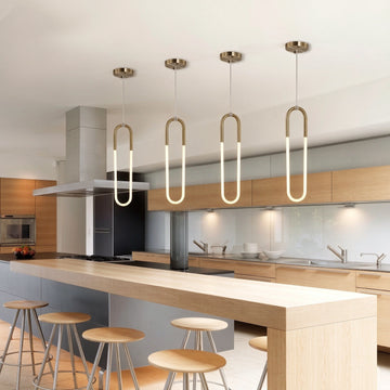 Four minimalist U-shaped gold pendant lights above modern kitchen island, brass finish white jade glass LED hanging lamps, contemporary open-plan kitchen interior lighting scene