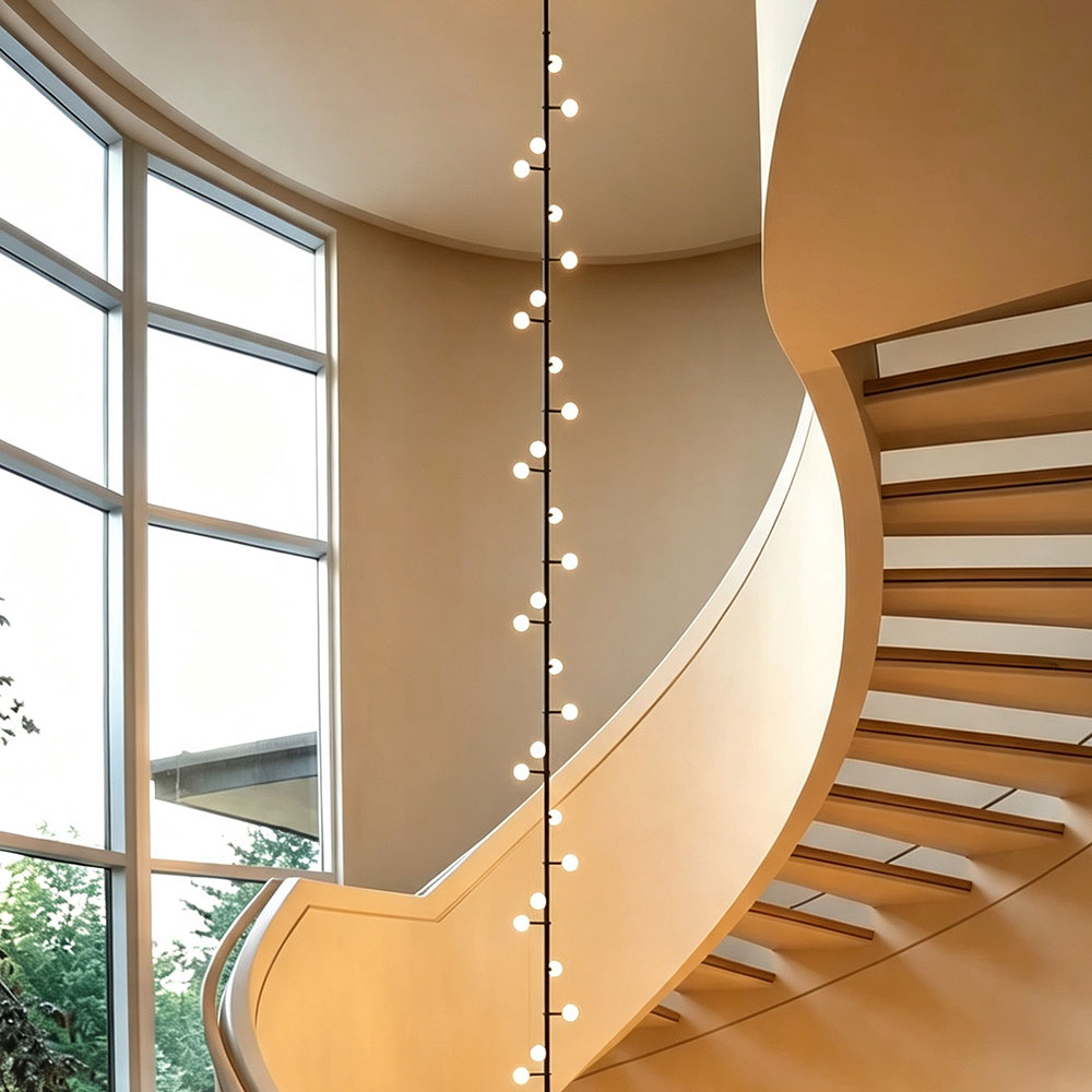 Modern extra‑tall vertical linear globe chandelier lit up for grand spiral staircase high ceiling luxury residential interior large window background