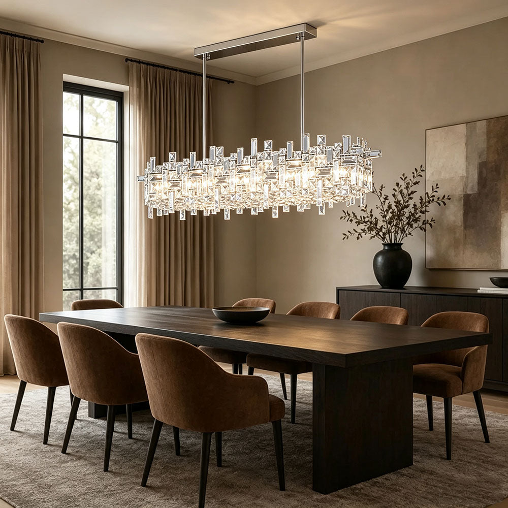 Modern Chrome Rectangular Crystal Chandelier, crystal pendant light with polished chrome frame, warm glowing fixture above large dark wooden dining table, neutral tone luxury dining room interior.