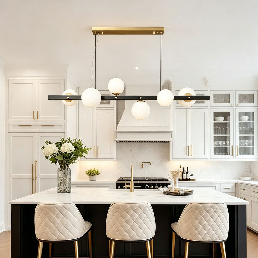 Black gold linear globe chandelier over modern white‑black two‑tone kitchen island, opal frosted glass globes, two‑tone metal pendant light for transitional style kitchen