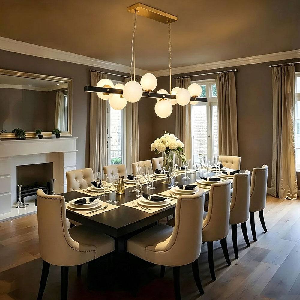 Black gold linear globe chandelier over modern white‑black two‑tone kitchen island, opal frosted glass globes, two‑tone metal pendant light for transitional style kitchen